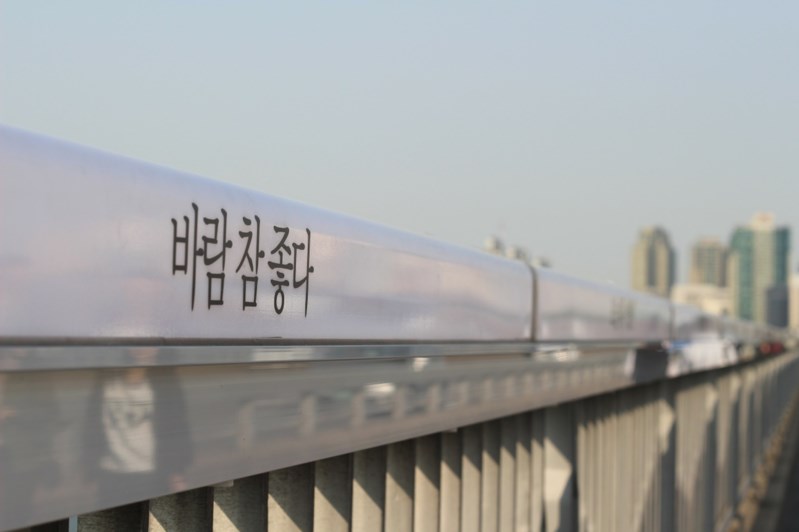 首爾市政府為了預防民眾自殺,2012年起在屢傳憾事的麻浦大橋上的安全欄杆寫滿防治標語,然而效果逐漸減低,最後在2019年被撤下。圖為麻浦大橋自殺防治標語「風真好啊」,用以轉換企圖輕生者的心情。(圖取自Pixabay圖庫)