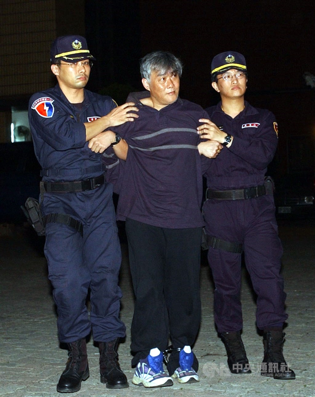 綽號「穿山甲」的前槍擊要犯詹龍欄(中)經法務部與宜蘭監獄陳報34次假釋案,服刑18年後終獲假釋出獄。圖為民國91年詹龍欄被警方押解返台。(中央社檔案照片)