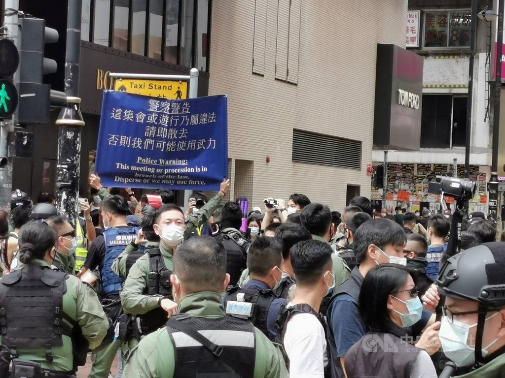 香港網友1日發起多區集會遊行,銅鑼灣東角道一帶,有數百名防暴警察戒備,不時驅趕個別穿黑衣示威者。圖為防暴警察舉起藍旗,警告市民不要聚集。中央社記者張謙香港攝 109年10月1日