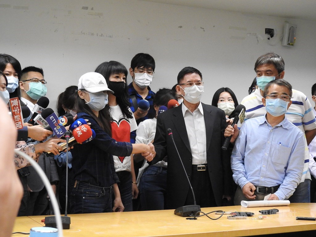 康軒文教集團疑藉「吹哨者」事件施壓女員工離職風波,勞資爭議調解會12日於新北市政府召開並協調成功,女員工(戴帽者)和康軒行政長蔡其修(前右2)握手和解。中央社記者王鴻國攝 109年10月12日