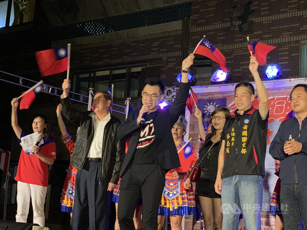 國民黨主席江啟臣(前中)17日晚間出席桃園市復興啟程聯歡會,與台上來賓一同高歌並揮舞小國旗。中央社記者葉臻攝 109年10月17日