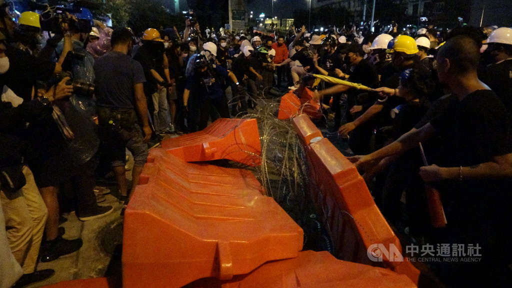 泰國民眾21日下午無預警遊行到總理府前要總理帕拉育下台,遭遇警方以鐵絲網阻擋,民眾隨後以拒馬壓倒鐵絲網突破警方防線。中央社記者呂欣憓曼谷攝 109年10月21日