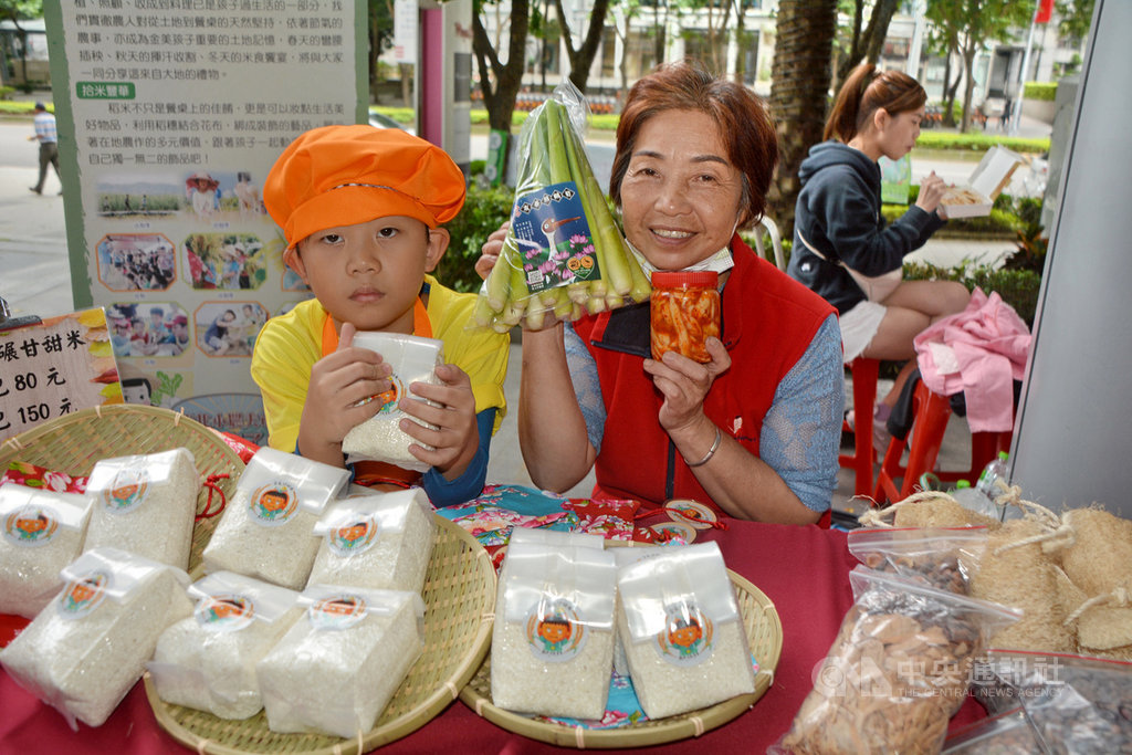 109年度新北市小農夫市集24日在板橋大遠百外登場,金山區金美國小附幼學童(左)穿起橘色廚師裝,現場推廣自己插秧、照顧、施肥、除草、收割的「金美甘甜米」。中央社記者黃旭昇新北市攝 109年10月24日