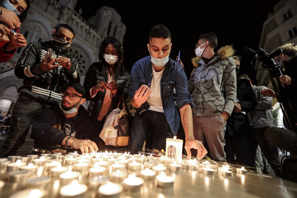 法國29日發生一連串攻擊事件,尼斯天主教堂內發生恐怖攻擊,3人遭殺害;亞維儂、里昂也傳出攻擊者持武器在街上揮舞威脅的事件。圖為民眾在巴黎聖母院大教堂外點燃蠟燭,悼念尼斯攻擊案的3名受害者。(法新社)