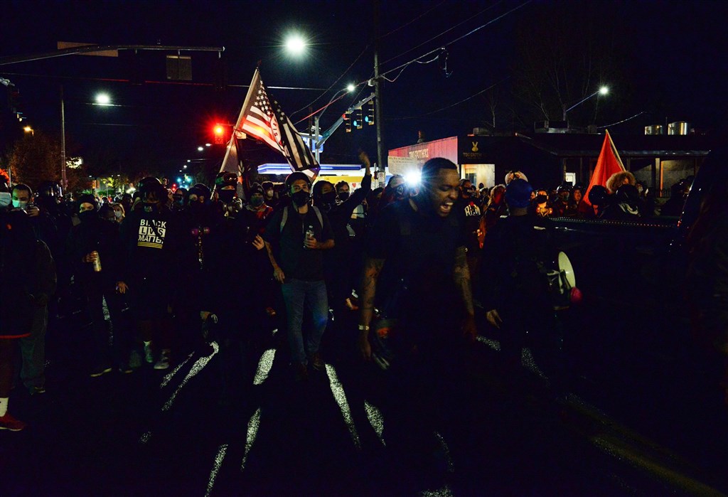 美國總統大選開票陷入膠著，俄勒岡州首府波特蘭深夜不平靜，手持突擊步槍的示威民眾高喊抗議口號繞行市區並焚燒國旗。（法新社）