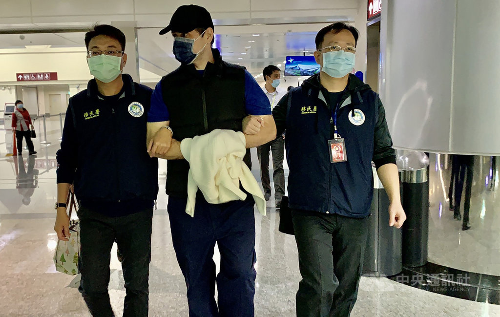 第一銀行ATM盜領案的羅馬尼亞籍犯嫌米海爾(Colibaba Mihail)(中)14日在台服刑完畢,移民署將人帶往桃園機場,晚間8時許把米海爾遣送出境;依相關規定,米海爾至少7年不可再入境台灣。(翻攝畫面)中央社記者劉建邦傳真 109年11月14日