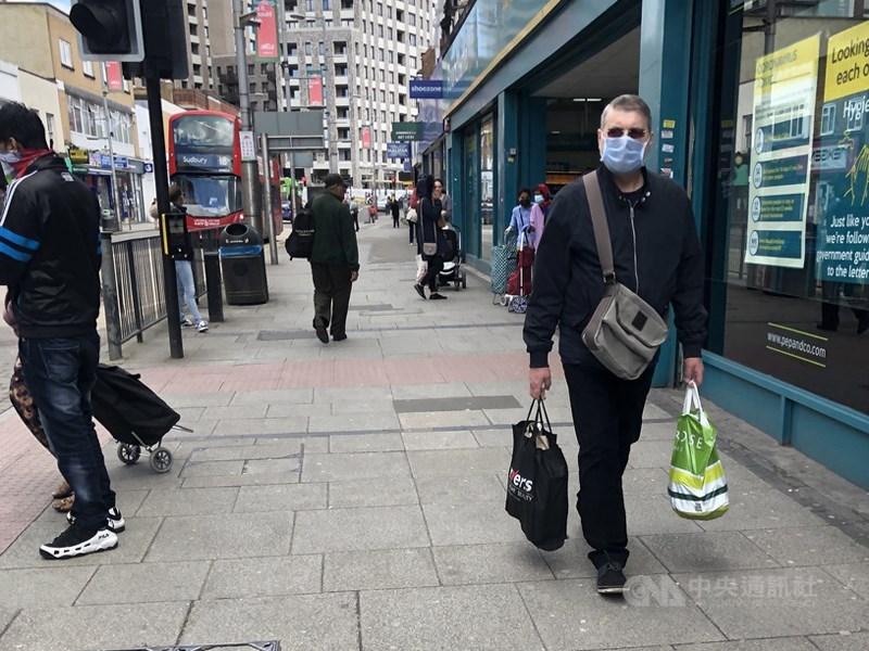 英國牛津大學研究人員表示,曾感染武漢肺炎的人,至少6個月內不太可能再次染疫。圖為5月英國倫敦民眾戴口罩上街採買。(中央社檔案照片)