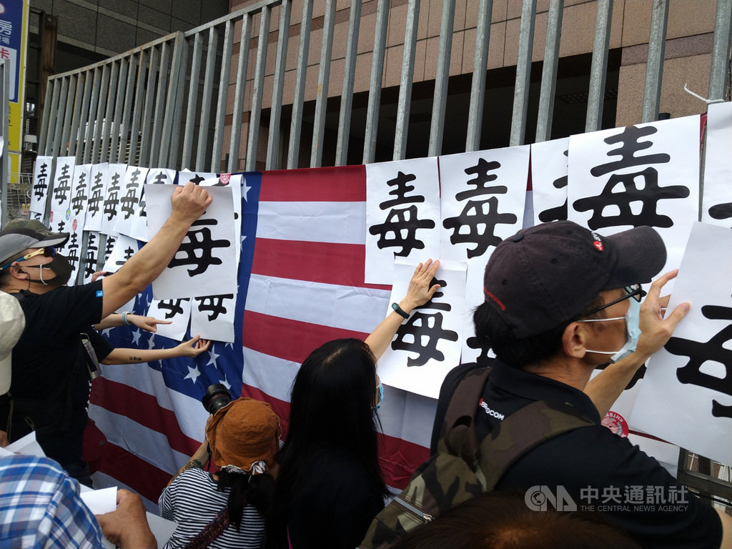 「秋鬥」遊行22日登場,主辦單位在終點站民進黨中央黨部前的隔離柵欄上掛起美國國旗,並請現場民眾將手上的「毒」字牌貼在上方,象徵「美國毒豬」進口。中央社記者張雄風攝 109年11月22日