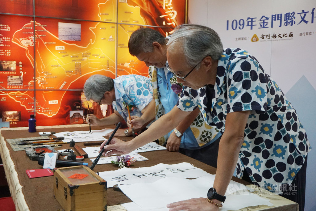 金門縣文化局長許正芳(右)24日出席109年文創商品成果展,身穿設計靈感來自金門花磚的花襯衫,在以高粱製成的宣紙上揮毫。中央社記者黃慧敏攝 109年11月24日