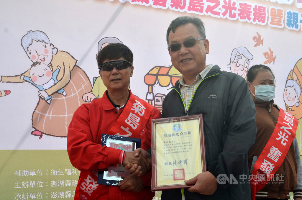 73歲退休老師林泰良(左)患有中度視障,教導社區與身障民眾學習薩克斯風等樂器,獲頒今年菊島之光奮發獎,28日在澎湖縣國際身障日系列活動接受縣長賴峰偉(右)表揚。中央社 109年11月28日