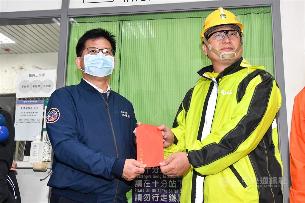 台鐵瑞芳-猴硐路段經過多日搶修,14日清晨恢復單線雙向通車,交通部長林佳龍(左)發紅包慰勞同仁。中央社記者鄭清元攝 109年12月14日