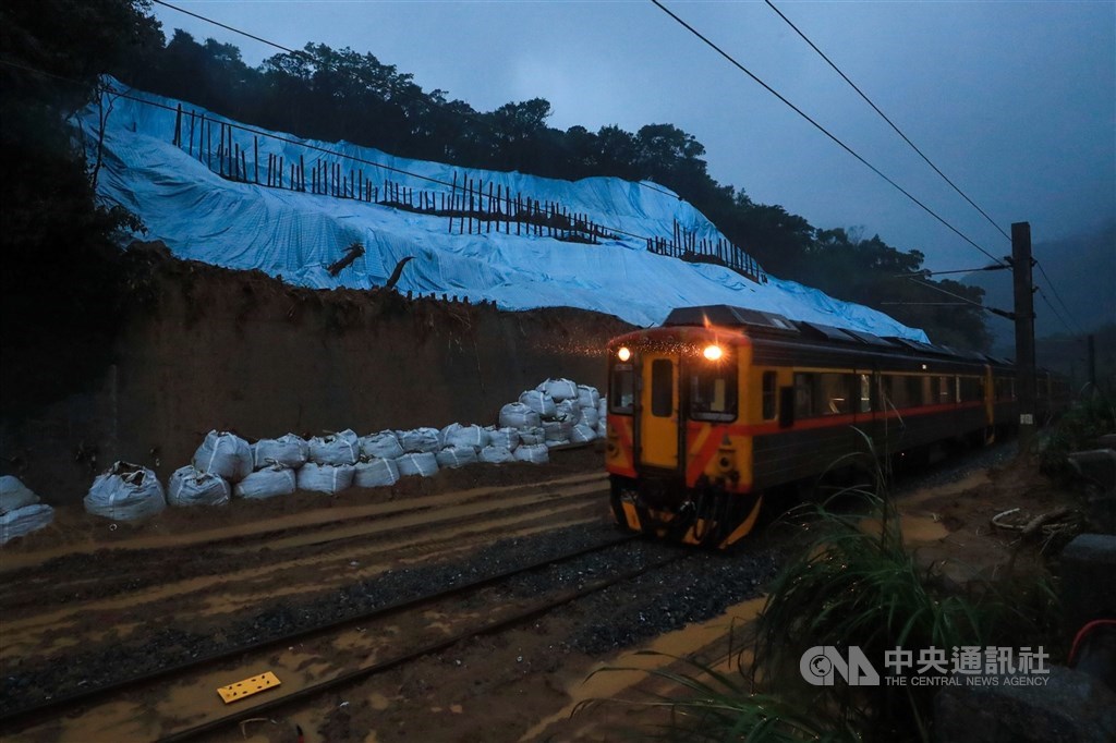 台鐵瑞芳-猴硐路段的邊坡4日嚴重崩塌造成東部路線中斷,13日搶通東正線,圖為14日清晨復駛後列車行經邊坡崩落處。 中央社記者吳家昇攝 109年12月14日