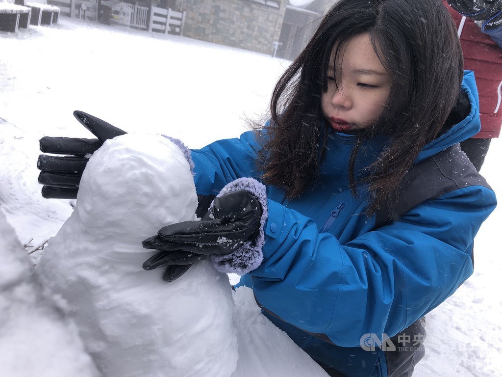 寒流來襲,海拔約1900公尺高的太平山國家森林遊樂區7日晚間開始下雪,8日一早已積雪3公分,民眾穿著禦寒衣物、戴著手套堆雪人。中央社記者王騰毅攝 110年1月8日