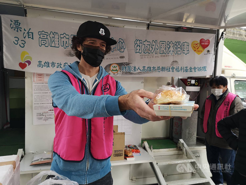來自澳洲的36歲兼職攝影師夏宇星(左)12日頂著寒風,在高雄市社會局及高雄市慈聯社會福利基金會三民街友中心幫忙下,拿著熱食、暖暖包及衣物給街友,他自願成為志工,服務街友付出奉獻。(高雄市政府社會局提供)中央社記者洪學廣傳真 110年1月12日