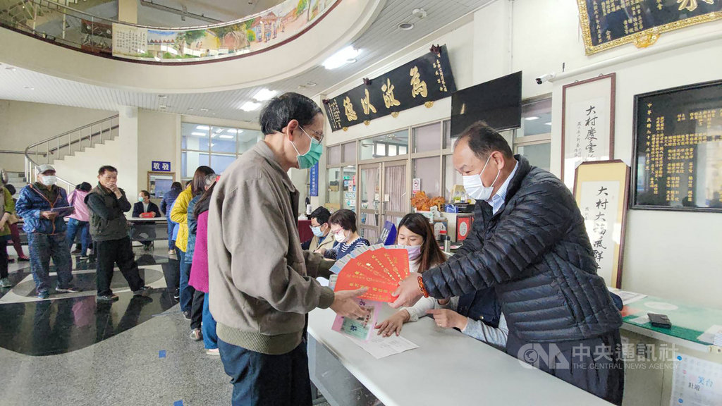 彰化縣大村鄉發放振興經濟暨關懷鄉民禮金,鄉民每人可領到新台幣2000元,鄉長游盛(右)親自把禮金交給排隊民眾。中央社記者吳哲豪彰化攝 110年1月16日