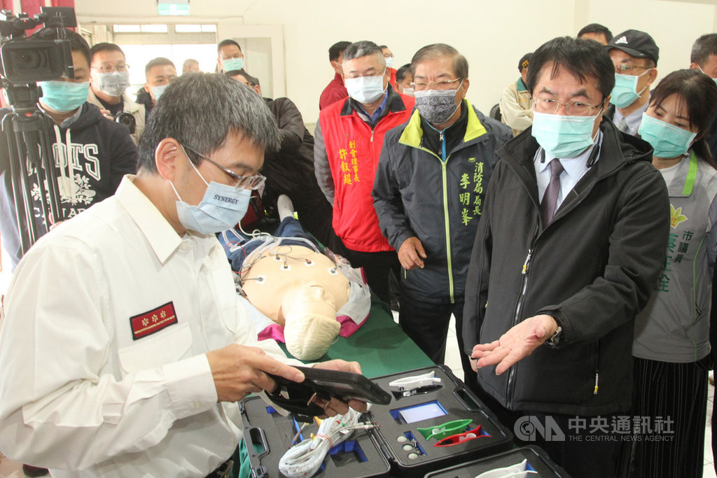 台南市政府消防局18日舉辦12導程心電圖機搶救冠心病患者感恩記者會,台南市長黃偉哲(前右)聽取消防人員解說相關設備。中央社記者楊思瑞攝 110年1月18日
