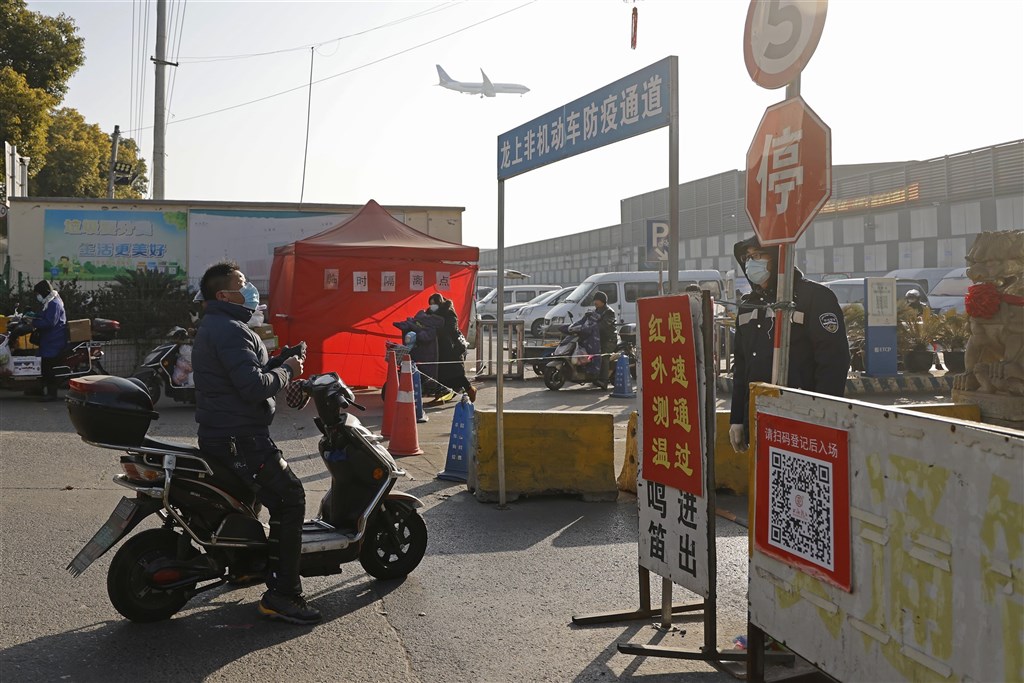 上海21日新增3例武漢肺炎確診病例,一處居民區列為中風險地區,且居民將集中至賓館隔離;主動篩查出病例的兩家醫院已暫停門診。圖為上海民眾進市場前,通過防疫通道。(中新社)