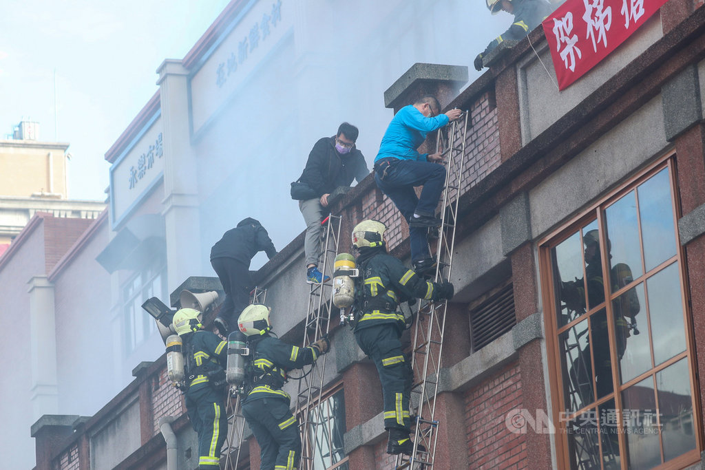 台北市消防局「一年一度年貨大街消防演習」22日在永樂市場舉辦,情境演習假設永樂市場商家桶裝瓦斯破裂爆炸起火引燃攤架,火勢延燒到永樂市場,消防人員架梯實施人員救助。中央社記者吳家昇攝 110年1月22日