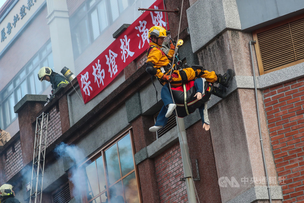 台北市消防局「一年一度年貨大街消防演習」22日在永樂市場舉辦,情境演習假設永樂市場商家桶裝瓦斯破裂爆炸起火引燃攤架,火勢延燒到永樂市場,消防人員以繩索垂降救援。中央社記者吳家昇攝 110年1月22日