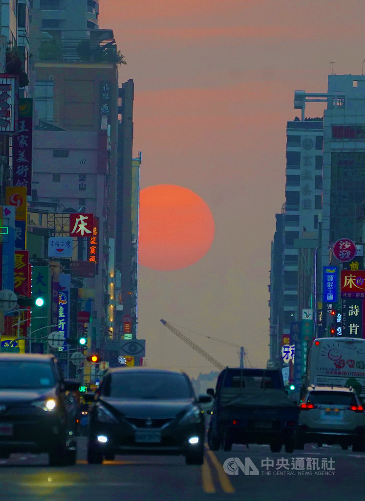 高雄市青年路「懸日」景象28日傍晚再次登場,吸引許多攝影愛好者前往取景拍攝,橘澄夕陽與傍晚略顯灰濛的街道相互輝映,對比明顯,形成美麗景致。中央社記者董俊志攝 110年1月28日