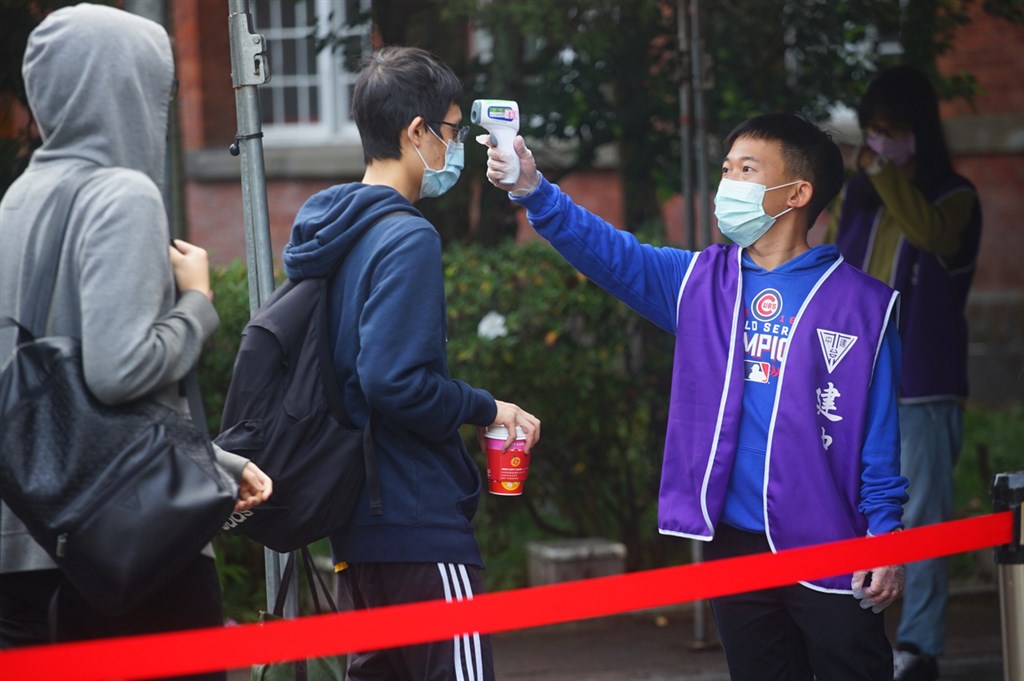 110學年度學測成績24日公布,各科拿到最高15級分的人數都比109學年度減少。圖為1月23日考生在試場入口處依序排隊等待量額溫。(中央社檔案照片)