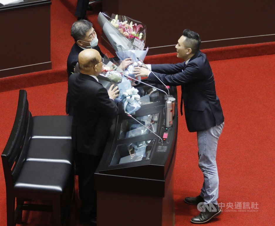 國民黨立委陳以信(右)5日在立法院會質詢時,特別送上花束給一同備詢的行政院長蘇貞昌(左前)與衛福部長陳時中(左後)。中央社記者施宗暉攝 110年3月5日