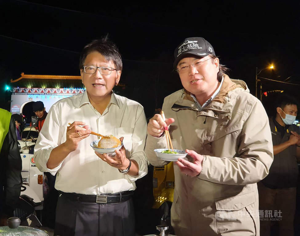 基隆市長林右昌(右)挑戰「24小時不斷電台灣縱走切西瓜」行程,13日晚間抵達終點屏東墾丁,與屏東縣長潘孟安(左)一起行銷南北2城市,分別品嚐屏東和基隆肉圓。中央社記者郭芷瑄攝 110年3月13日