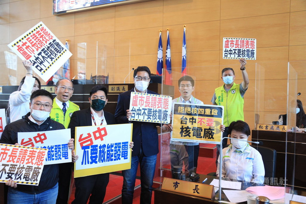 民進黨台中市議會黨團16日在市議會臨時會中，到市府官員備詢席旁舉牌，要求台中市長盧秀燕（前右）表態是否支持核四重啟等議題。中央社記者郝雪卿攝  110年3月16日