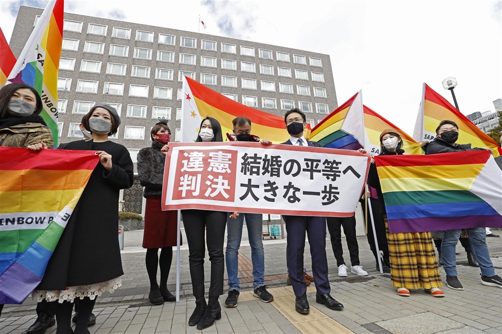 札幌地方法院17日一審判決日本政府不承認同性婚姻違憲,原告辯護律師與支持者在法院前舉出「婚姻平權跨出重大一步」布條。(共同社)