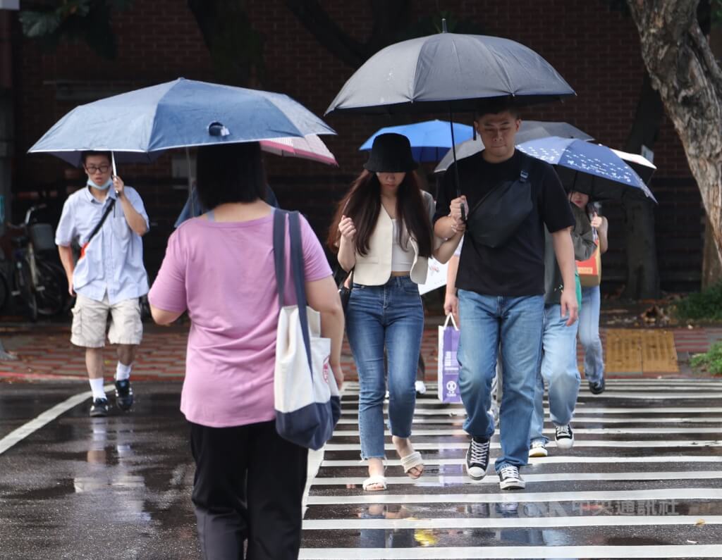 圖為北市大安區街頭民眾撐傘快步通過馬路。（圖／中央社）