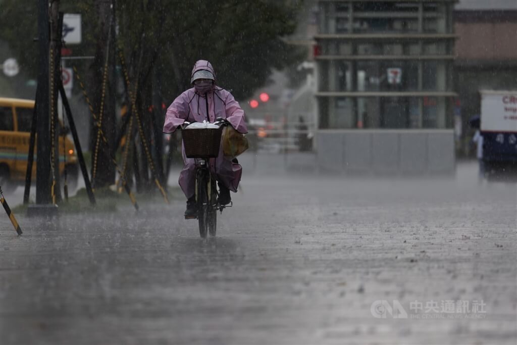 圖為台北市午後下起一陣大雨，信義區民眾穿雨衣騎腳踏車。（圖／中央社）