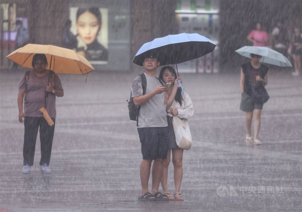 圖為台北市大直區民眾撐傘駐足在滂沱雨勢中。（圖／中央社）