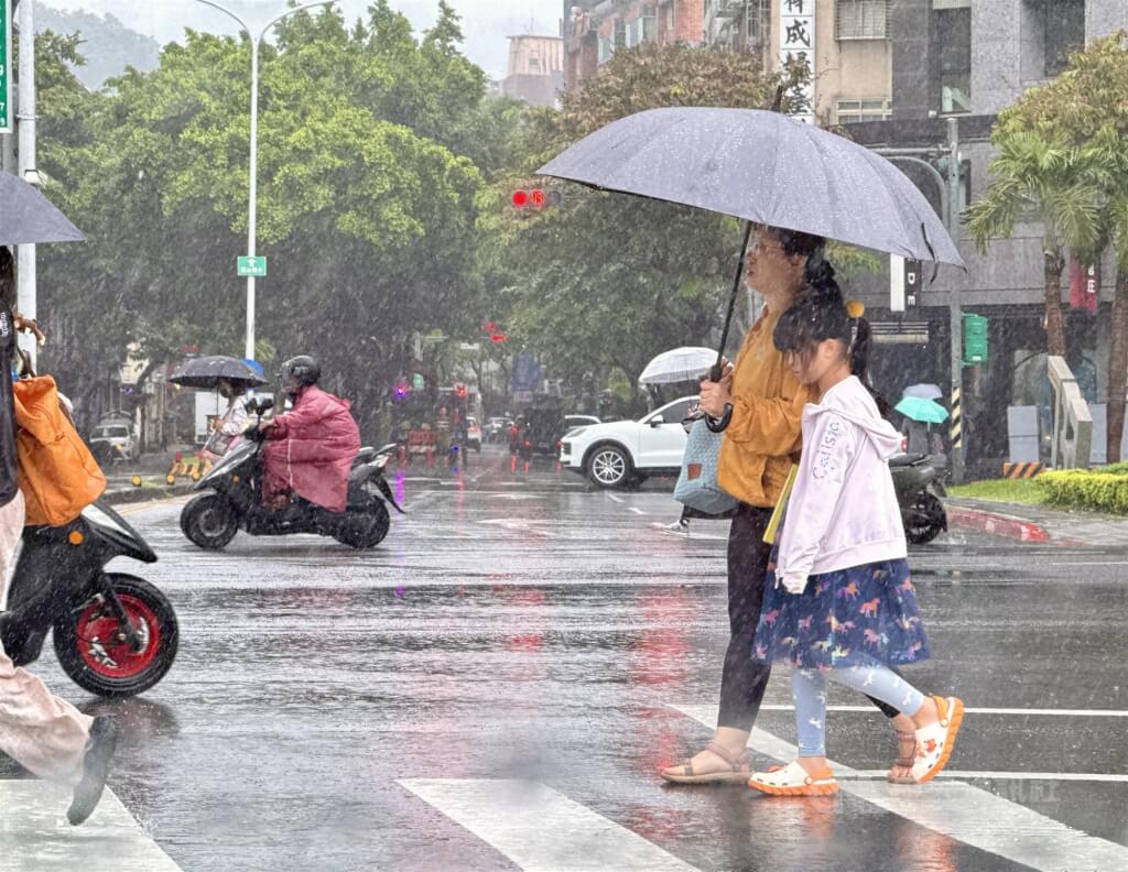 氣象署17日表示，受東北季風影響，18日桃園以北、宜蘭整天陰雨，北北基宜防局部大雨，預估最冷的時間點將在19、20日清晨。圖為17日台北內湖區街頭，民眾撐傘過馬路。中央社記者王飛華攝　114年11月17日