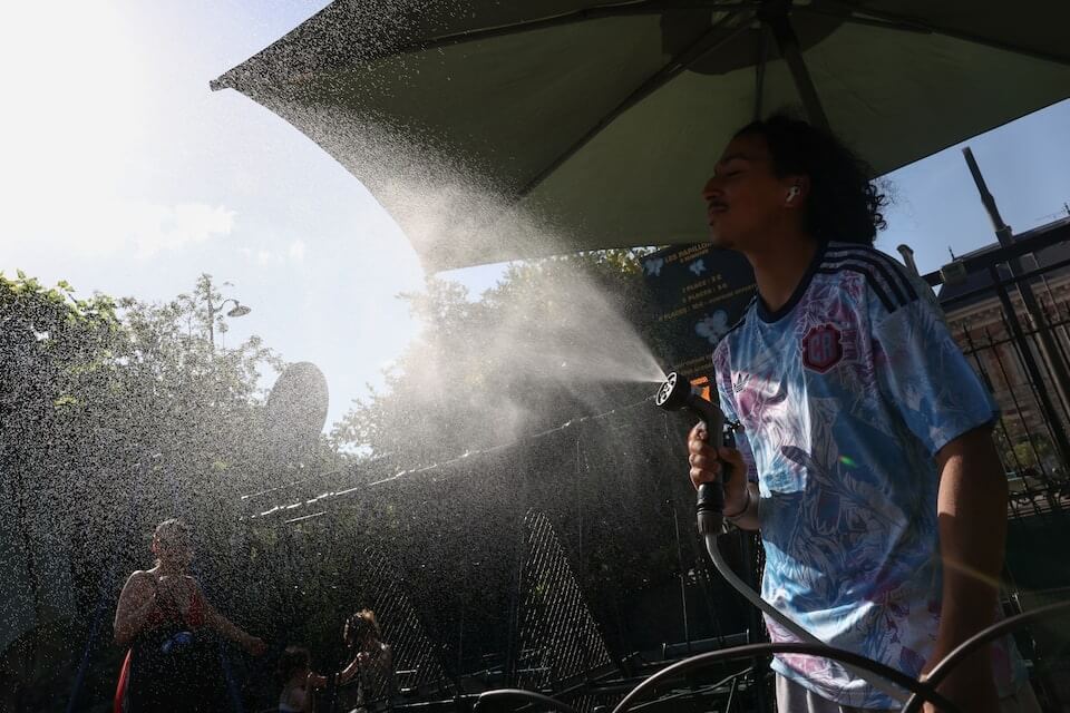 法國巴黎25日氣溫高達攝氏35度,民眾噴水降溫。(路透社)