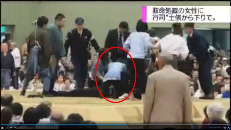 日本舞鶴市長4日在相撲表演場地「土俵」內昏倒，具護士資格的女性（紅圈者）進場急救，卻被裁判以廣播請下來。（圖取自NHK網站 www.nhk.or.jp）