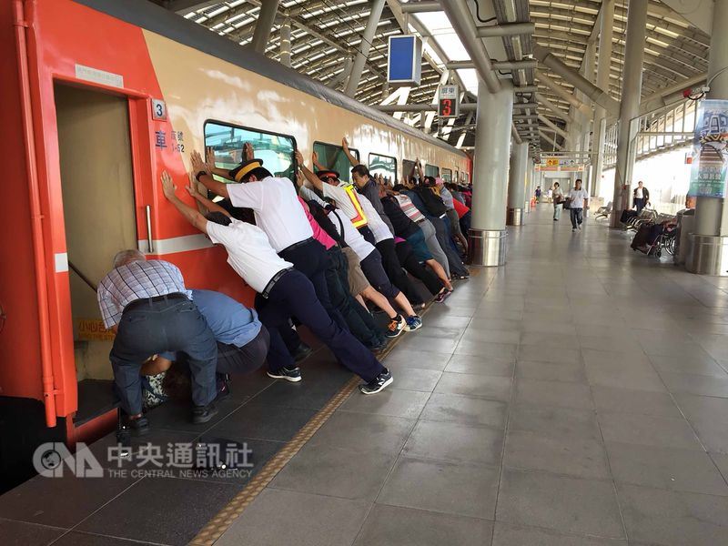 台鐵屏東站27日上午有一名婦人強行推折疊門要上車,由於火車在緩慢行駛中,婦人滑落卡在月台與火車間空隙,列車緊急停駛,台鐵工作人員與月台上其他旅客合力推車廂救人。(台鐵提供)中央社記者汪淑芬傳真 107年5月27日