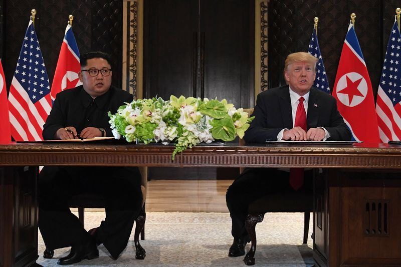 美國總統川普12日與北韓領袖金正恩舉行歷史性峰會,兩人共同在媒體面前簽署文件。(法新社提供)