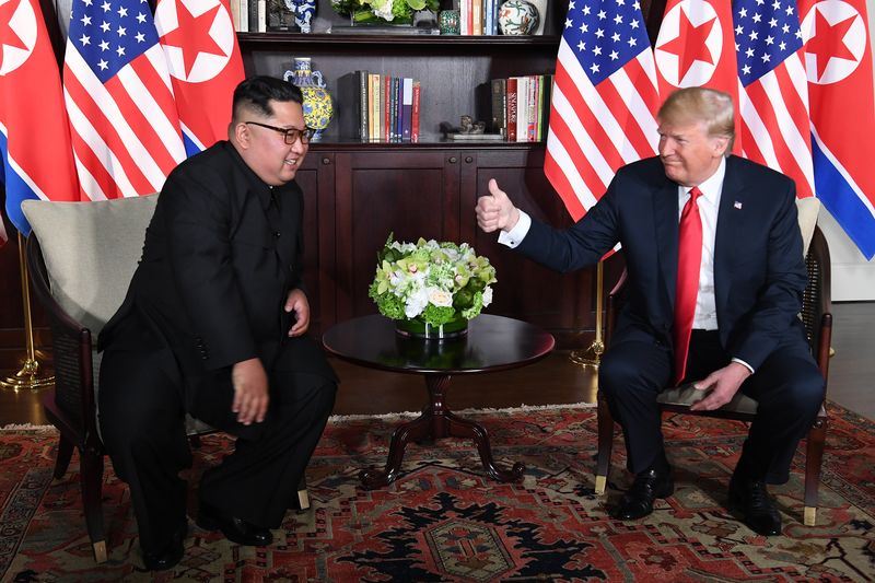美國總統川普(右)與北韓領導人金正恩的歷史性峰會,兩人稍早進行約35分鐘的私人會面,川普會後對媒體表示「會談進行得非常好」。社群媒體則廣傳一張川普坐著對金正恩豎起大拇指的照片。(法新社提供)