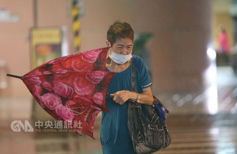 颱風瑪莉亞10日來襲,台北市區下午開始陸續有間歇雨勢,晚間風雨增強,且不時有強陣風,街頭撐傘民眾被瞬間強風吹歪了傘。中央社記者鄭傑文攝 107年7月10日
