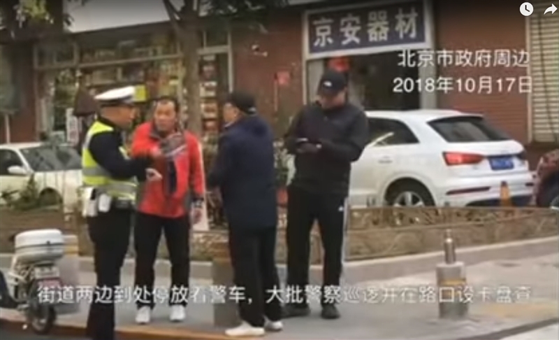 中國P2P投資人17日再度聚集北京,試圖在北京市政府前陳情。不過,現場附近已布署大批警力,員警更在人行道上逐一攔下行人盤查身分。(圖取自美國之音YouTube網頁youtube.com)