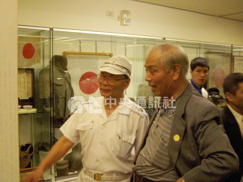 許昭榮(左1)2004年曾穿著重新訂製日本軍服,參加國史館台灣文獻館「烽火歲月」特展,仔細觀看各項戰爭史料文物。(中央社檔案照片)