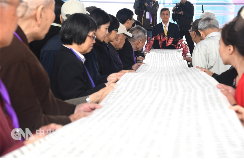 副總統陳建仁(後中)9日在促轉會於白色恐怖景美紀念園區第二波有罪判決撤銷公告活動中,和受難者家屬一起展開布滿1505名撤銷刑事有罪判決者姓名的書卷,正式宣告抹除受難者不法判決的汙點。中央社記者孫仲達攝 107年12月9日