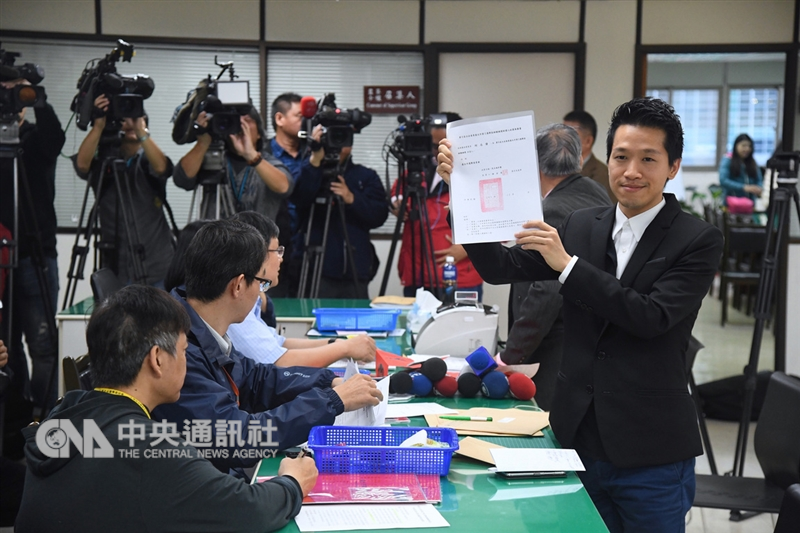 民進黨台北市議員何志偉(前右)14日赴台北市選舉委員會登記參選台北市第2選區立委補選,登記時何志偉展示政黨推薦書。中央社記者王飛華攝 107年12月14日