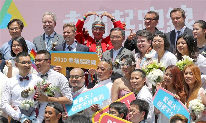 同婚登記24日開跑,同婚團體婚姻平權大平台與台北市政府民政局在信義廣場舉辦「幸褔起跑線Wedding Party」,同運先驅祁家威(後中,紅衣者)到場祝賀新人。中央社記者裴禛攝 108年5月24日