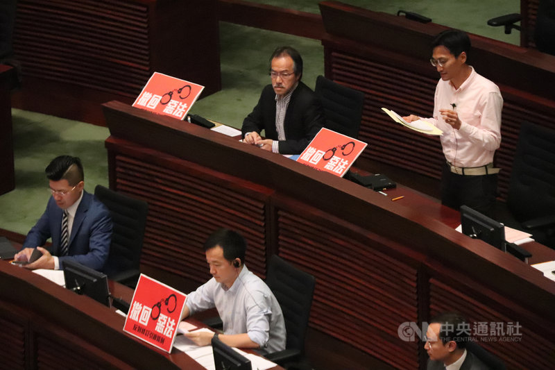 圖為修訂草案在香港立法會進行一、二讀時,泛民議員舉標語反對。(中央社檔案照片)