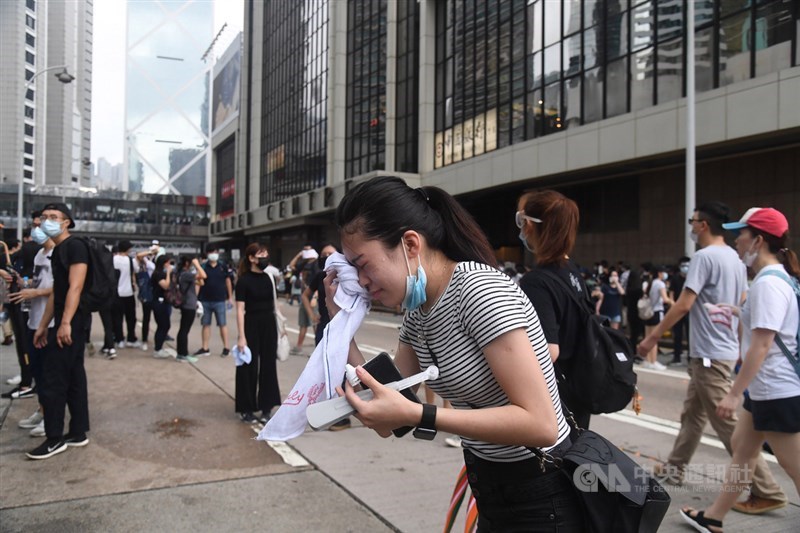 香港警方12日下午對集結抗議反送中的民眾作法轉趨強硬,近4時左右施放催淚彈,有民眾經不住催淚彈刺激,趕緊拿出毛巾擦臉。中央社記者王飛華攝 108年6月12日