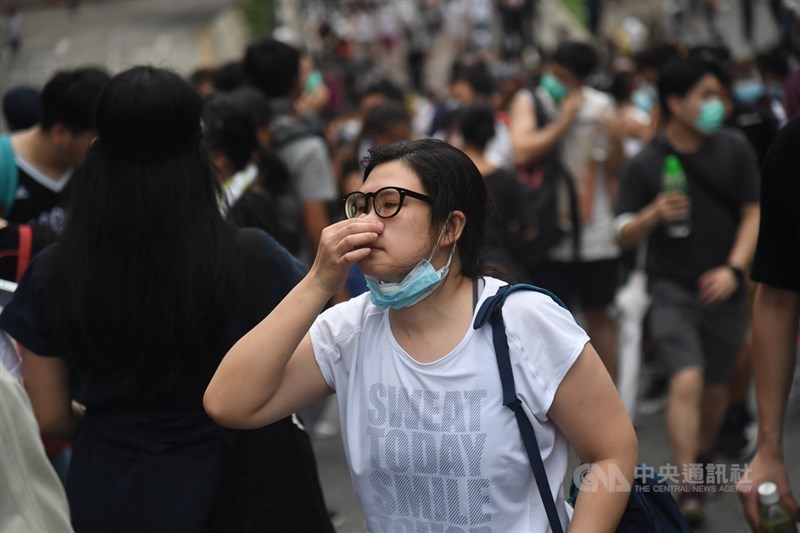 香港警方12日下午對集結抗議反送中的民眾作法轉趨強硬,近4時左右施放催淚彈驅離抗議人潮,周邊有民眾捏著鼻子前進。中央社記者王飛華攝 108年6月12日