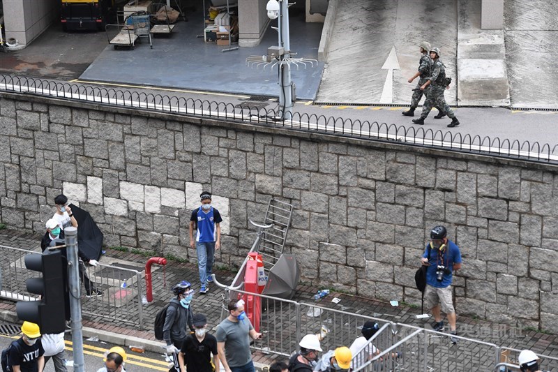香港民眾繼9日發起「反送中」大遊行後,12日再度集結抗議,占領立法會外周邊區域及主要幹道,下午當地警方展開驅離,另一頭隔著圍牆有解放軍巡邏。中央社記者王飛華攝 108年6月12日