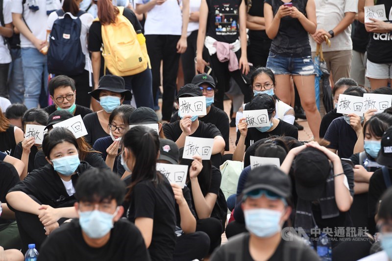 香港反送中抗議潮延燒,繼9日大遊行後,12日又有大批年輕人包圍立法會及占領主要幹道,部分抗議民眾在場席地而坐,手持「撤回」兩字標語表達訴求。中央社記者王飛華攝 108年6月12日