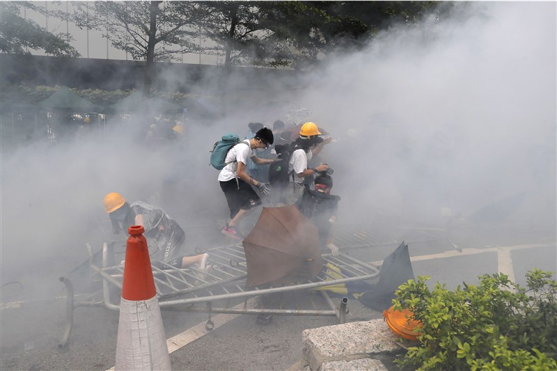 香港反送中示威12日下午衝突升高,警方在立法會旁對示威者施放催淚彈。(美聯社)